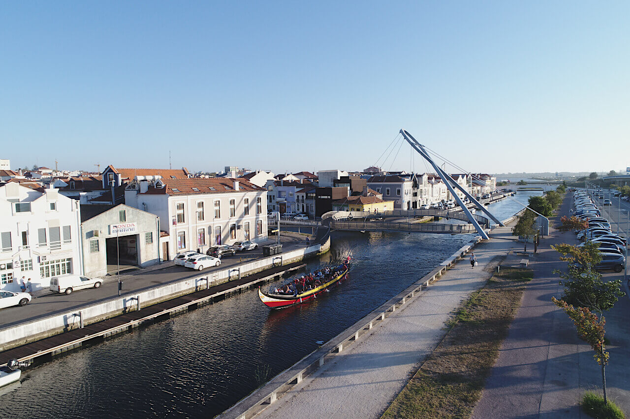 Vista dos canais da Ria de Aveiro, onde navega um moliceiro e da Ponte do Laço.
